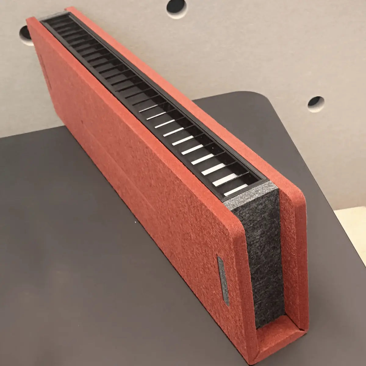 Red and black rectangular acoutsic light on a gray surface with a neutral background