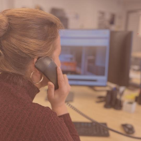 Person on the phone in front of a computer screen in an office setting